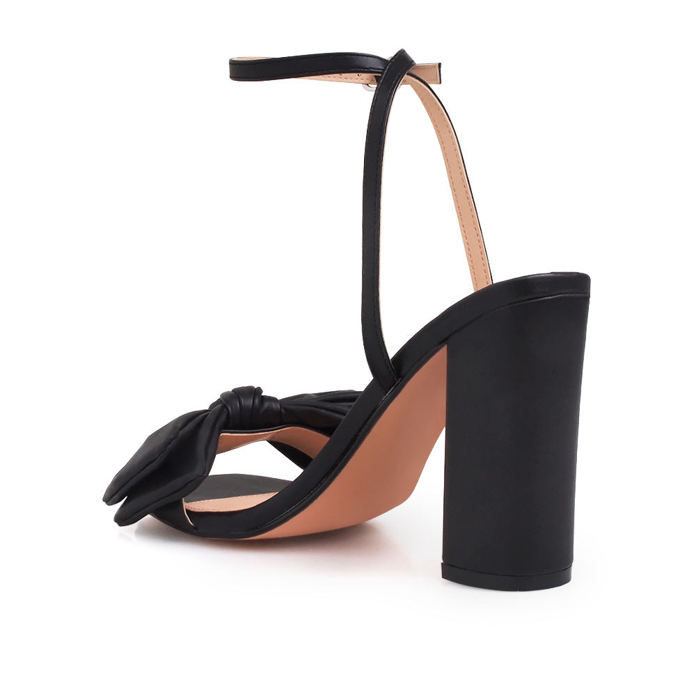 Black heels with bow design upper and ankle buckle clasp - back view