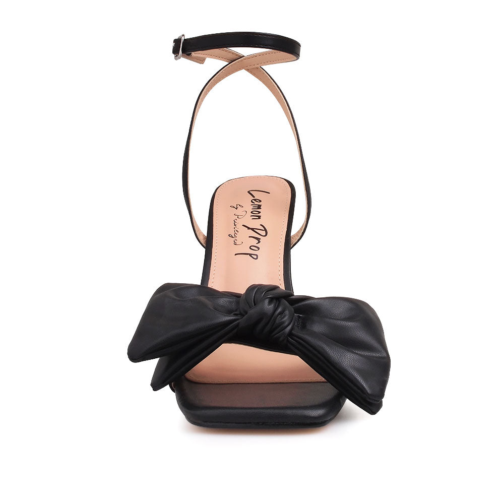 Black heels with bow design upper and ankle buckle clasp - front view