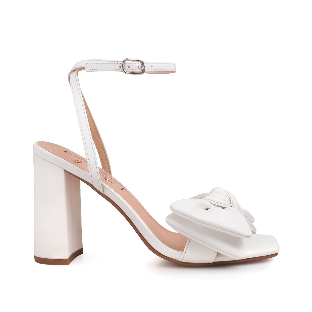 White heels with bow design upper and ankle buckle clasp - side view