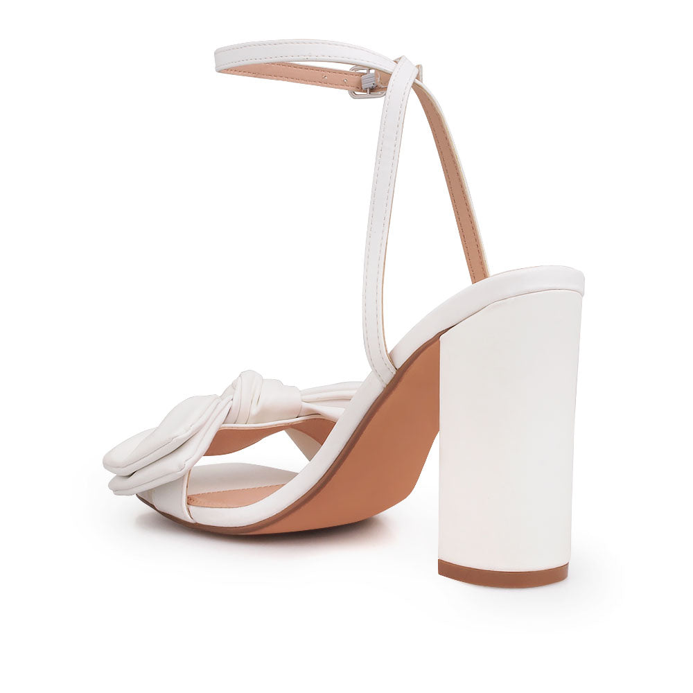 White heels with bow design upper and ankle buckle clasp - back view