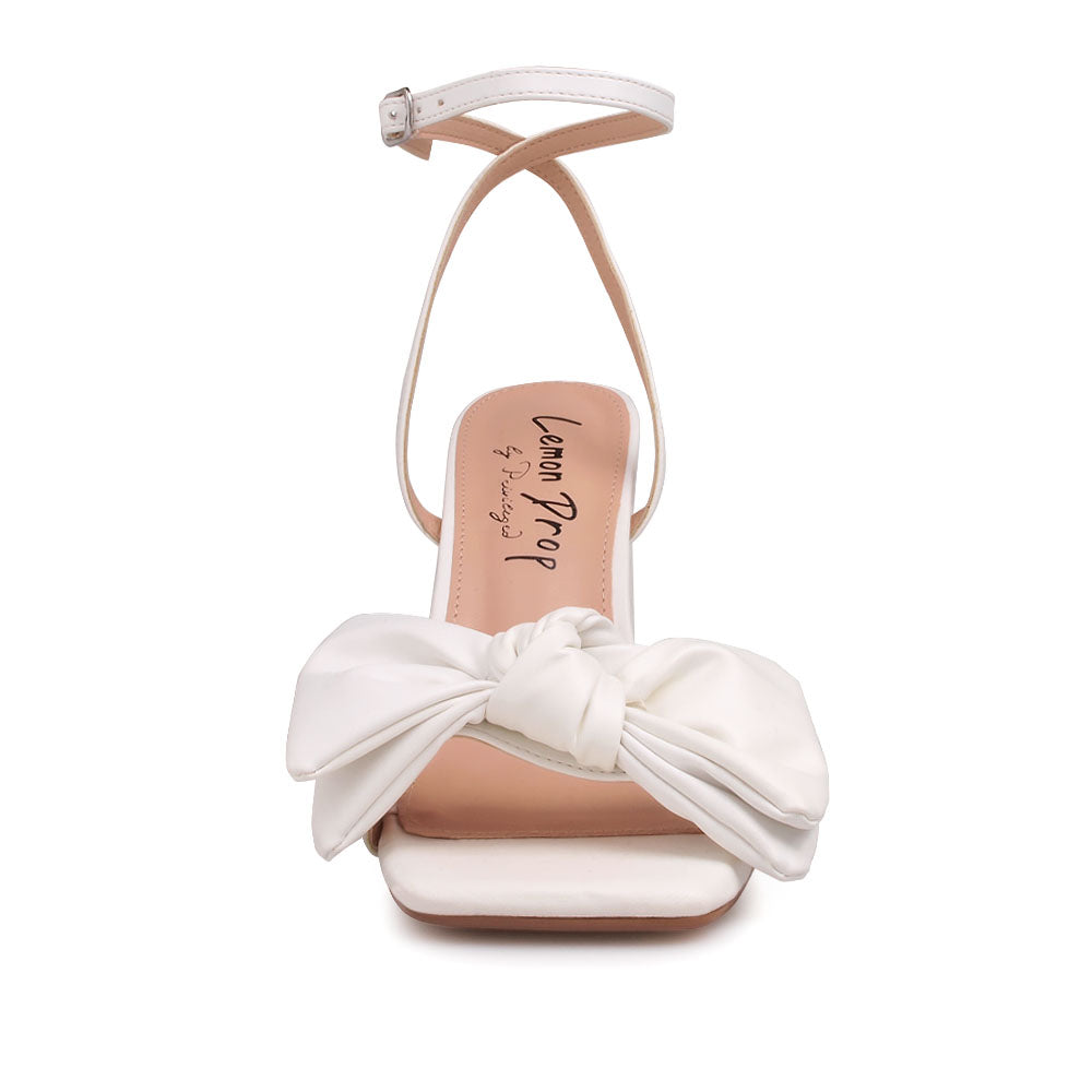 White heels with bow design upper and ankle buckle clasp - front view