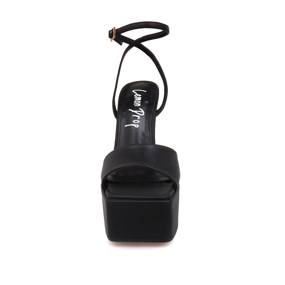 Black platform heels with open toe and ankle buckle closure - front view