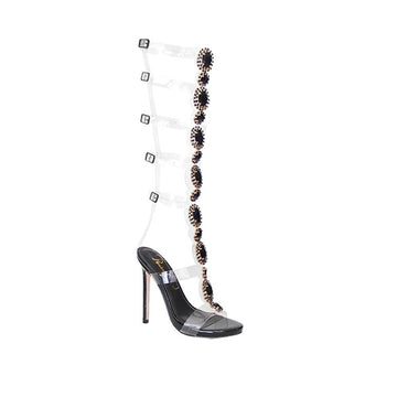Heels in black tone with knee-high jewel decoration and belt strap fastening