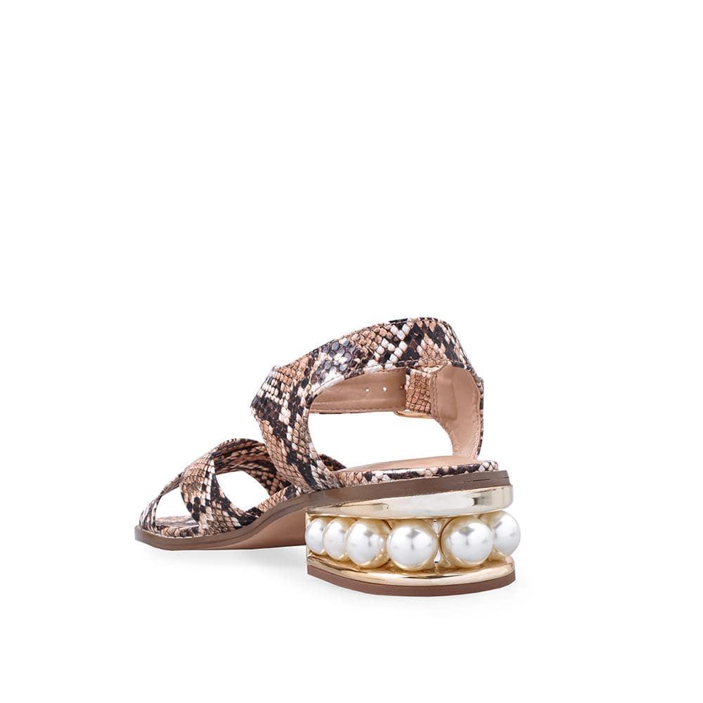 Women's tan-colored flat shoes with snake-patterned straps and a large pearl on the heel-posterior view