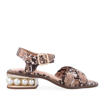 Women's tan-colored flat shoes with snake-patterned straps and a large pearl on the heel-side view