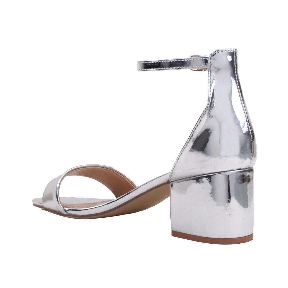 Flat metallic silver heels with an ankle buckle strap and an open toe-posterior view