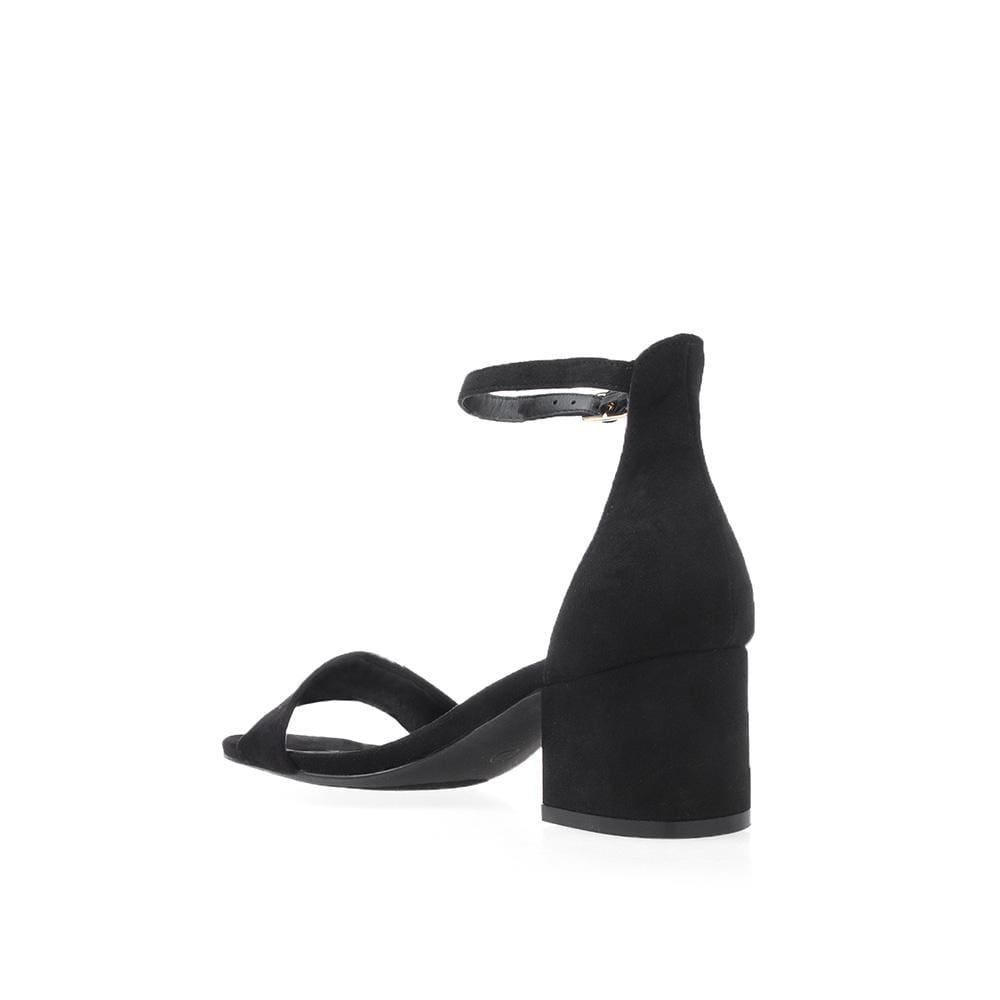 Plain black heel flats with a buckle ankle closure and a strapped open toe-posterior view