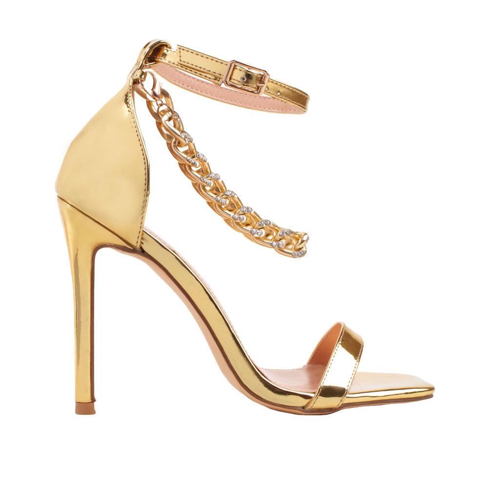 Women's golden high heels with a diamond-encrusted gold chain and ankle buckle closure.