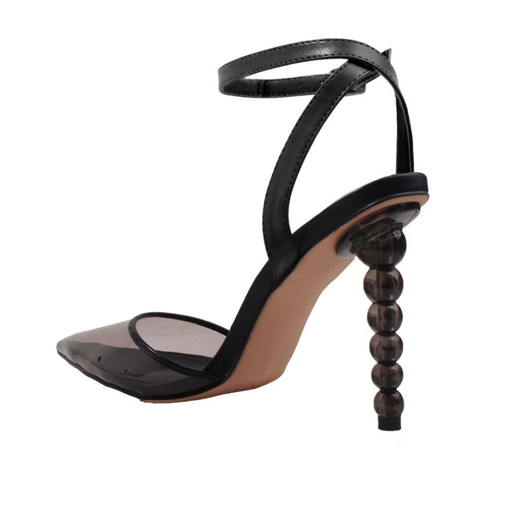 Women's black-colored heels with a closed-toed semi-transparent vinyl top and ankle buckle fastening-posterior view