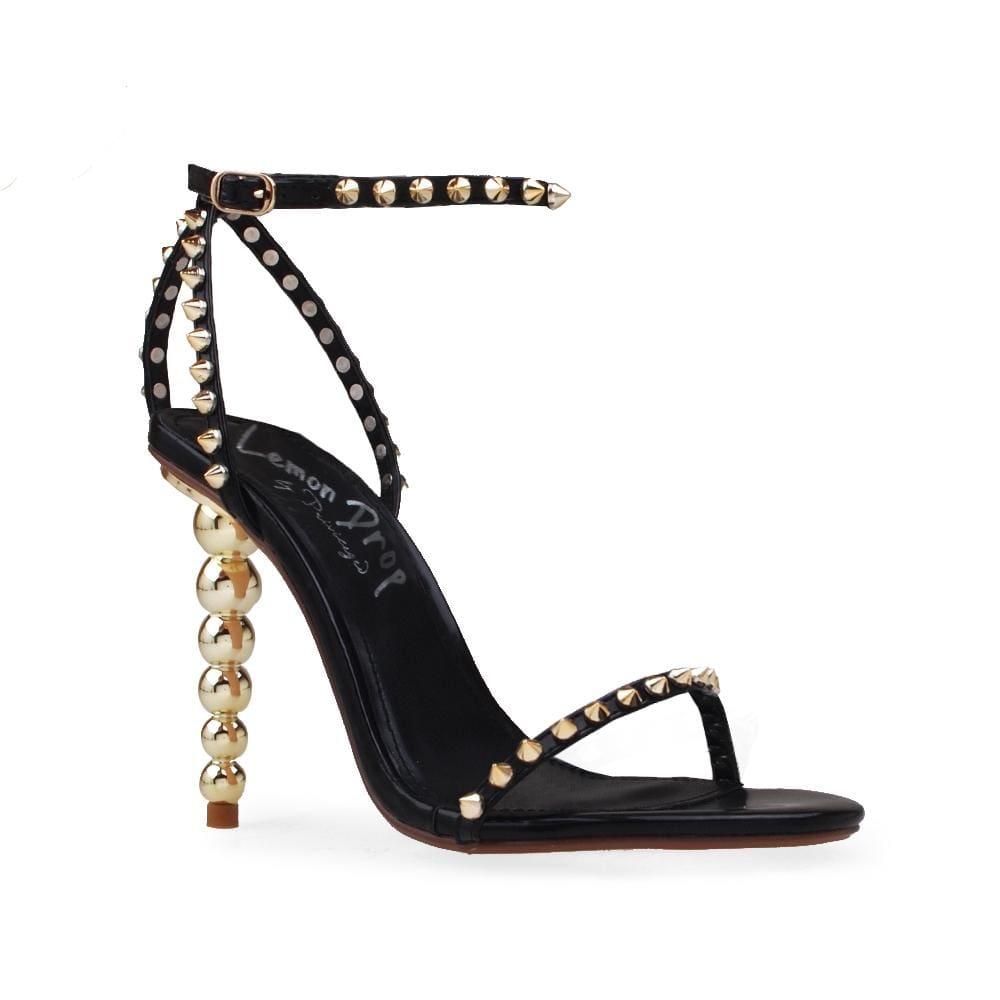 Women's open-toed pearled heels in black with a gold metallic studded ankle buckle fastening.-corner view