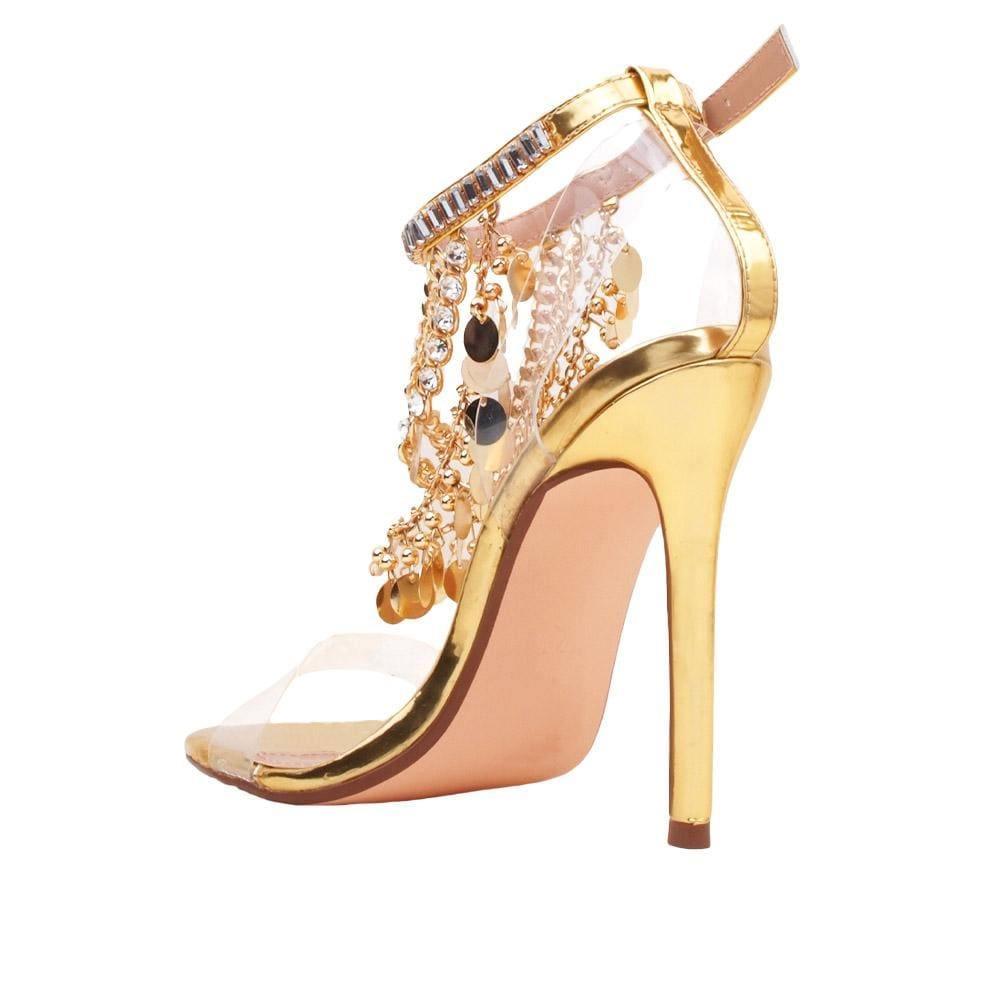 Golden-colored heel with clear strap gold chains, rhinestones, metallic gold charms upper, and ankle buckle fastening for women-posterior view