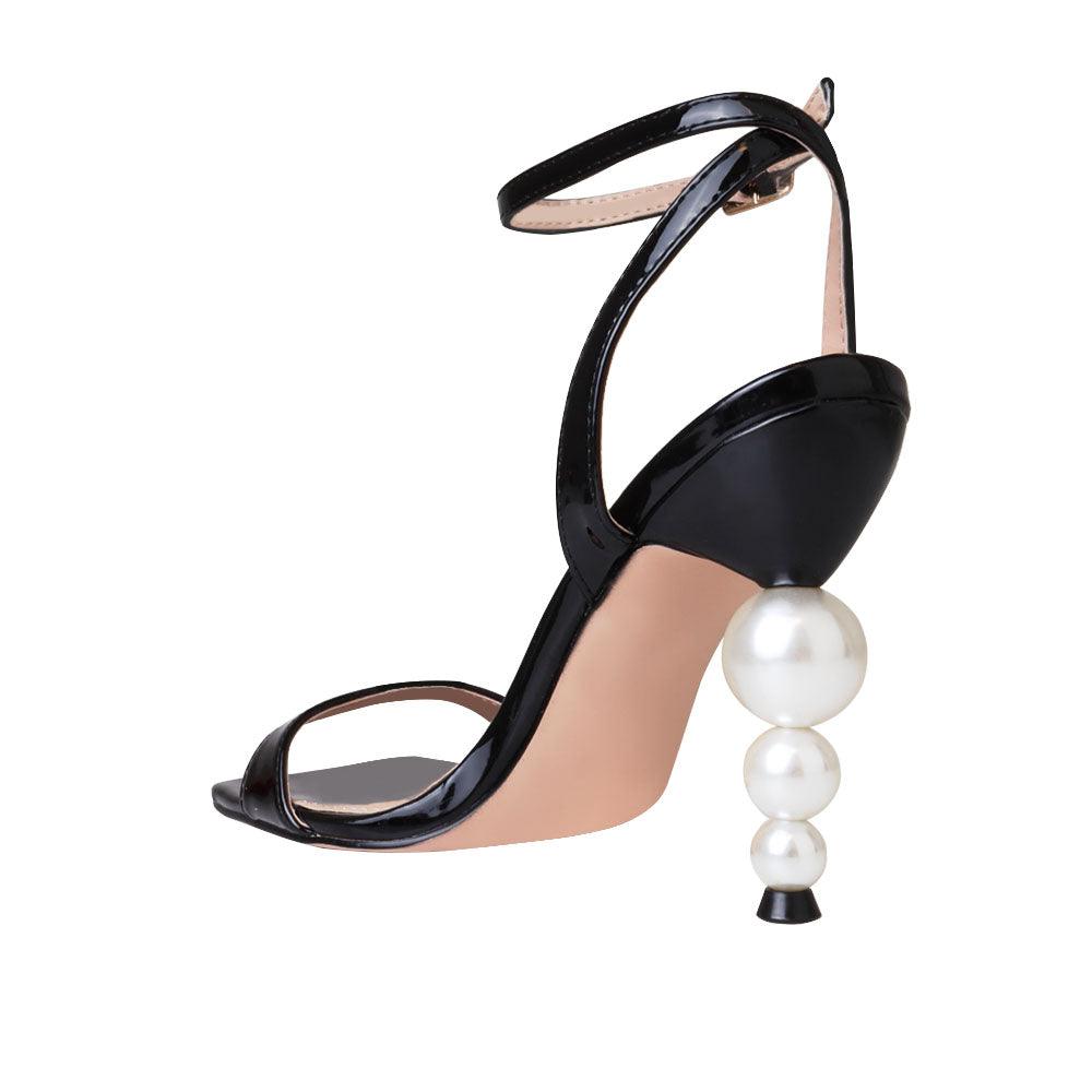 Black colored women heels with ankle buckle closure and three tiered pearl heel-posterior view