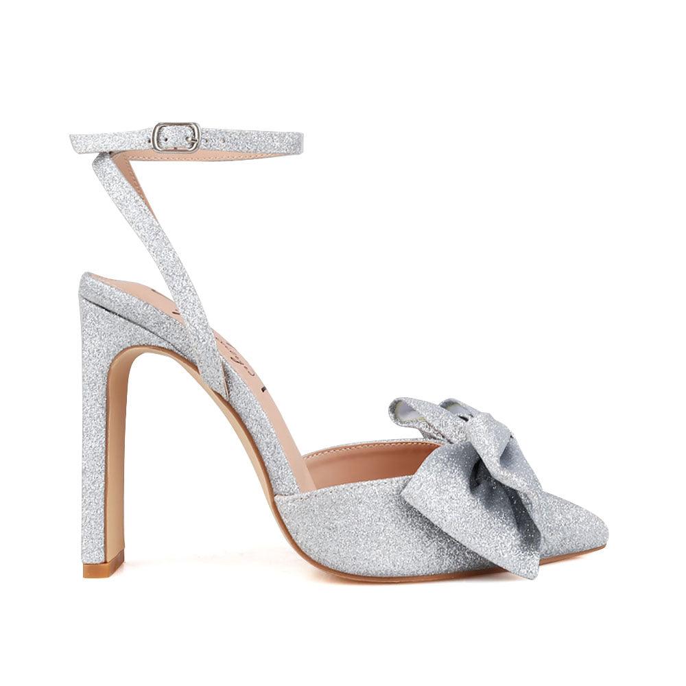 Silver glitter heels with pointed toe, bow top, and ankle buckle closure.