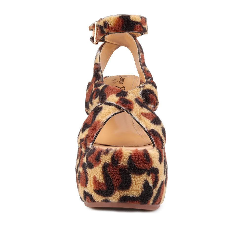 Upper platform crossed strap block heels with ankle buckle closure in leopard patterned shearling-front view