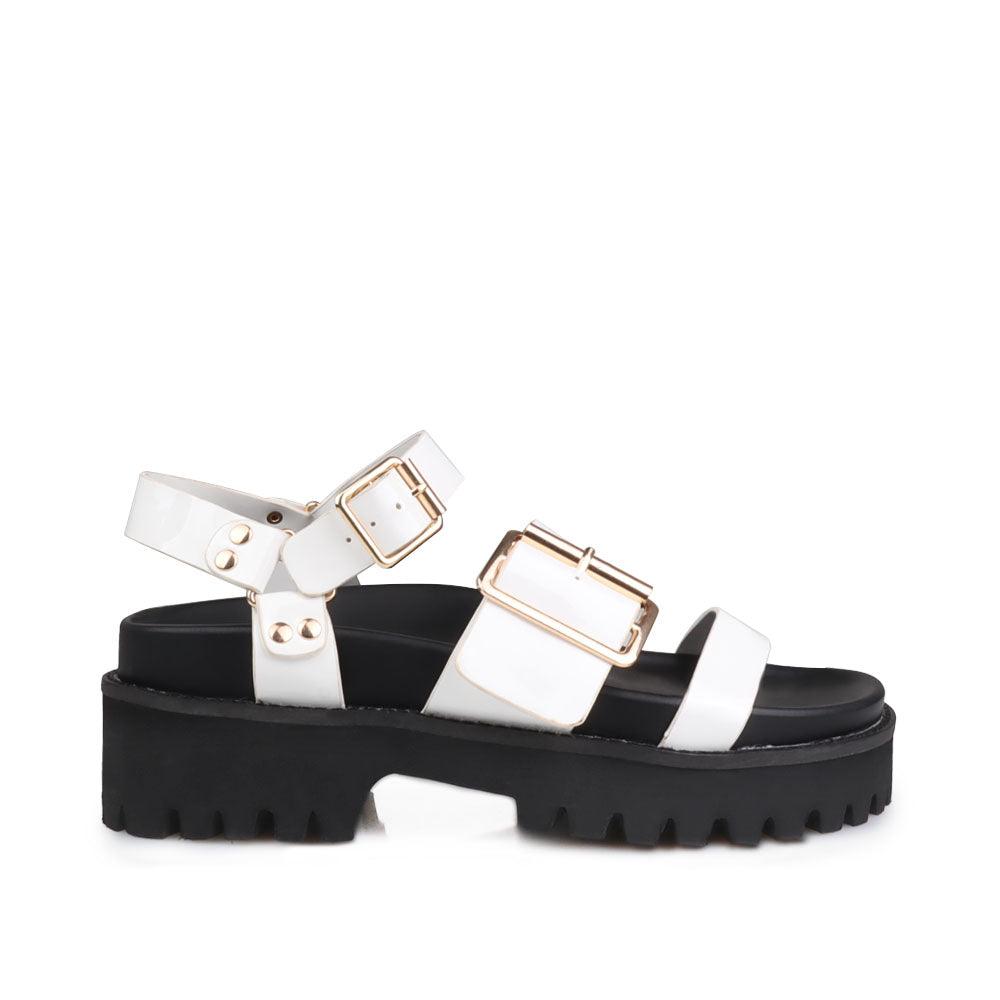 Women's white platform with buckle straps, ankle buckle closure, and black bottom-side view